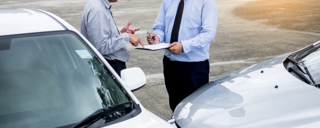 insurance agent writing on clipboard while examining car after accident claim being assessed and processed. insurance agent writing on clipboard while examining car after accident claim being assessed and processed.
